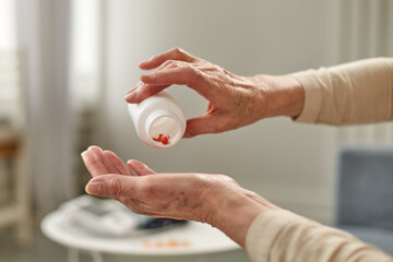 Senior woman sit on couch having daily vitamins or diet supplements at home, mature old female pensioner take dose of pills from meds bottle, elderly healthcare, medication concept