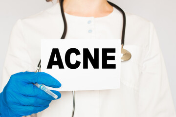 The doctor's blue - gloved hands show the word ACNE - . a gloved hand on a white background. Medical concept. the medicine