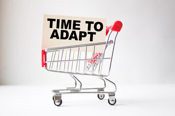 a business card with text TIME TO ADAPT in a shopping cart. business and finance