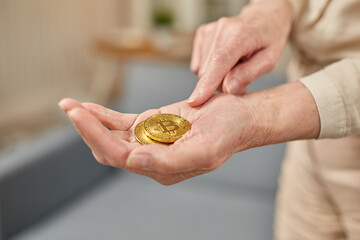 Old woman holds bitcoin coins in her hand. Senior citizen happy life concept