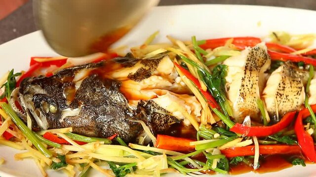 Pouring sauce on steamed  goby  fish, Thai famous food.