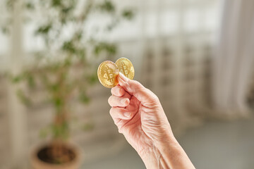 Old woman holds bitcoin coins in her hand. Senior citizen happy life concept