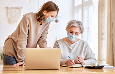 Anonymous women in masks using laptop and taking notes at home