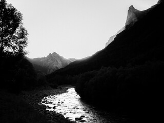 Imagen en blanco y negro infrarrojo digital de la puesta de sol sobre los picos, bosques y...