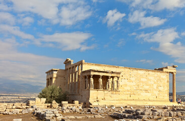 Fototapeta na wymiar Greece. General view of the restored temple of the Erechtheion in the ancient Athenian Acropolis (421-406 BC) against the background of a blue sky with clouds. Travel, excursions and sightseeing 