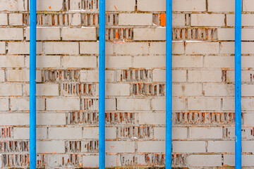 Texture of gray brick painted wall and four blue pipes, industrial background