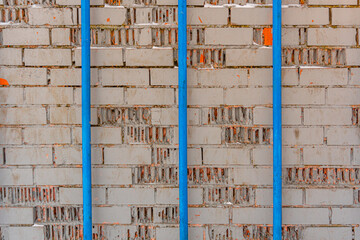Texture of gray brick painted wall and three blue pipes, industrial background