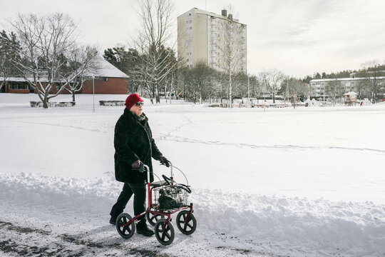 Senior woman with walking frame having walk at winter