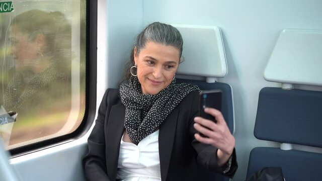 Smiling mature woman taking photo while riding in train