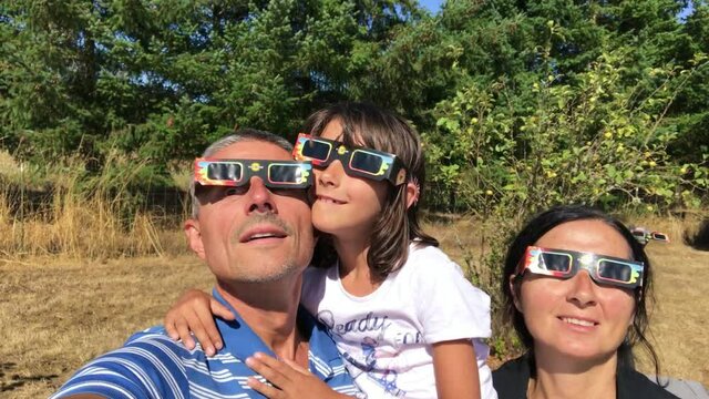Family watching total solar eclypse wearing eclipse glasses