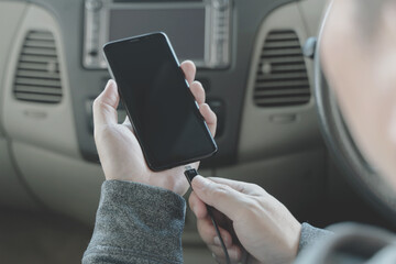 close up man hand holding charge the battery mobile smart phone in car.