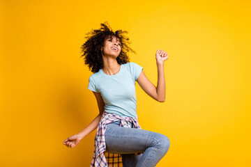 Photo of charming funky dark skin curly girl dressed blue t-shirt dancing isolated yellow color background