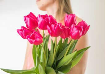 Beautiful young woman with tulip bouquet. Spring portrait. Bright pink flowers in girl's hands.