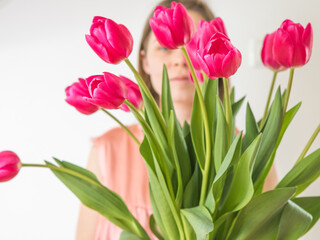 Faceless concept. Beautiful young woman with tulip bouquet. Spring portrait. Bright pink flowers in girl's hands.