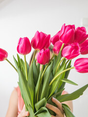Faceless concept. Beautiful young woman with tulip bouquet. Spring portrait. Bright pink flowers in girl's hands.