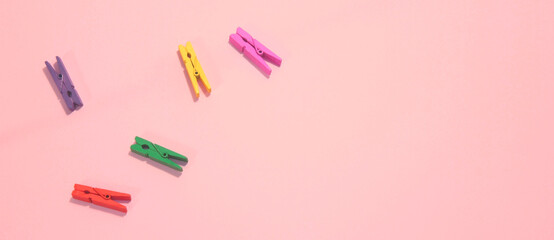 multi-colored clothespins on a pink background in minimalist style