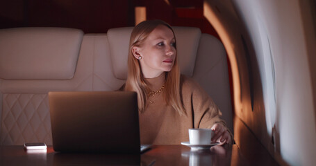Elegant businesswoman working on laptop flying first class late at night