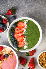 Matcha green tea breakfast superfoods smoothies bowl topped with strawberries, blueberries, coconut flakes Overhead, top view, flat lay