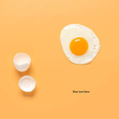 Fried egg and shells on a pastel yellow background. Creative layout. Minimalistic still life. Breakfast concept. Top view, flat lay, place for text.