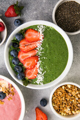 Matcha green tea breakfast superfoods smoothies bowl topped with strawberries, blueberries, coconut flakes Overhead, top view, flat lay