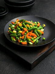 Stir-fried vegetables in a bowl. Mixed vegetable salad with green peas,been, corn, and carrot. Concept for a tasty and healthy vegetarian meal.