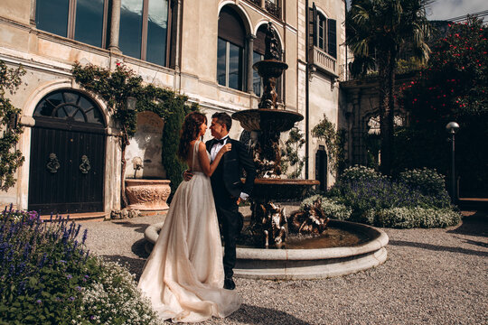 Walk of the newlyweds at the fountain against the backdrop of the old mansion. Summer sunny day.