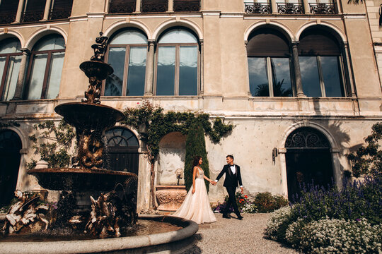 Walk of the newlyweds at the fountain against the backdrop of the old mansion. Summer sunny day.
