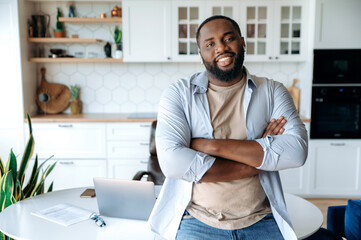 Friendly handsome confident stylish bearded African American male freelancer, standing near the...