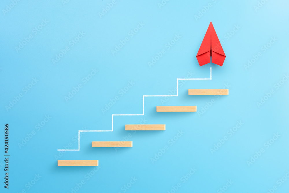 Wall mural wooden block stacking as step stair with red paper plane on blue background, ladder of success in bu