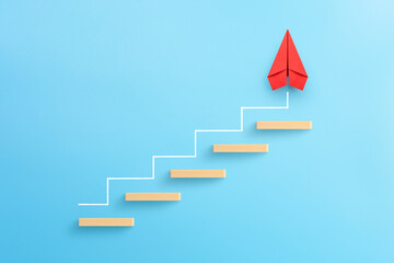 Wooden block stacking as step stair with red paper plane on blue background, Ladder of success in business growth concept, copy space
