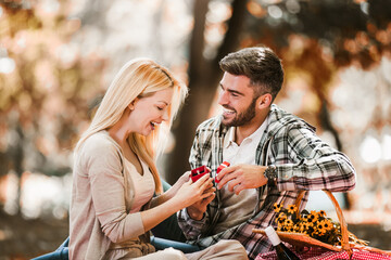 Loving young couple on a date with flowers and with a gift in the park