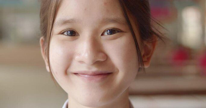 A young Asian teenage high school student girl is smiling happily.