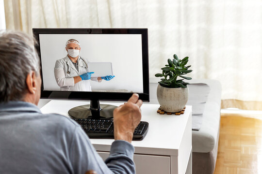 Caucasian senior man has medical consultation appointment by video call with his doctor. Elderly man sit in the living room at home have online consultation on computer with male doctor or physician.