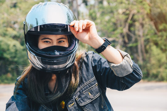 Young Asian woman wearing a motorcycle helmet before riding. Helmets contribute to motorcycle safety by protecting the rider's head.