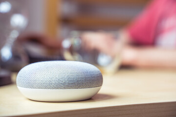 voice controlled smart speaker in a interior. male working in background