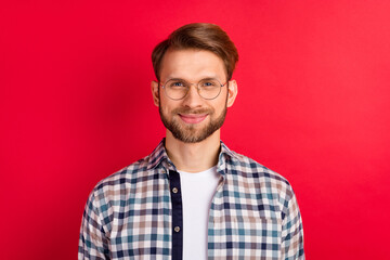 Photo of attractive handsome young gentleman dressed plaid shirt spectacles smiling isolated red color background