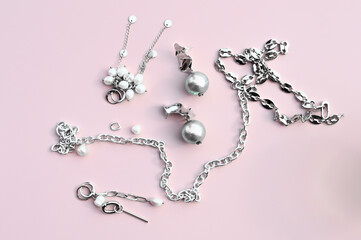 Stylish silver jewelry with pearls on pink background. Woman trendy fashion accessories arrangement. 