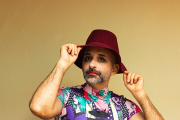 Candid portrait of man with makeup wearing red hat posing for the camera. Not binary