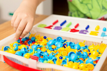 Obraz na płótnie Canvas By provided numbers boy inserting pins. Play at home. Implement for children to develop fine motoric skills, logical thinking through play. Learn counting and stimulate imagination, creativity.