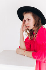 Close up fashion portrait of young beautiful blondie girl in red dress and black hat 