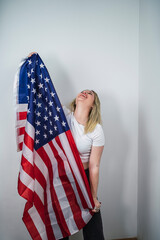 Chica guapa rubia con bandera americana feliz celebrando 4 de julio