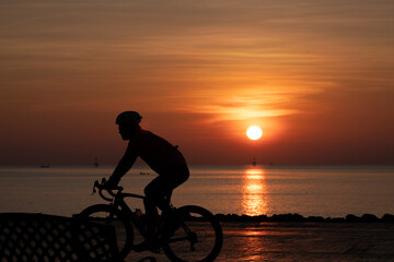 Fototapeta na wymiar silhouette man cycling in the morning and sunrise behind them