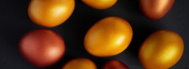 Golden Easter eggs close-up on a black background. Luxurious festive decor. Banner format