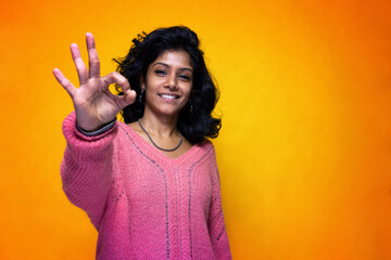 Beautiful Sri Lanka girl poses standing with yellow bright background- Young woman smiles doing ok
