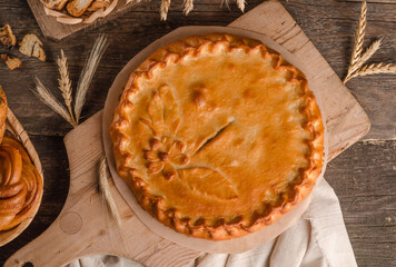 Delicious fresh round pie stuffed with curly dough decorations on wooden