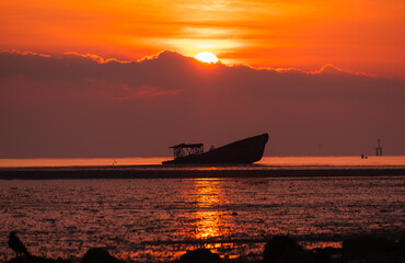 Naklejka premium A silhouette shipwreck on the beach and sunrise in the morning