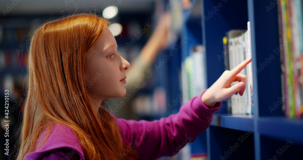 Poster redhead preteen schoolgirl selecting book in school library