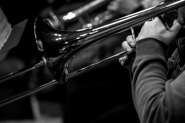 Hands of a musician playing the trombone close-up in black and white