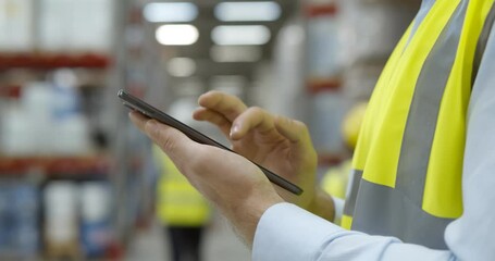 Close up of warehouse worker using mobile phone at workplace - Powered by Adobe
