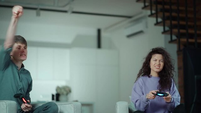 happy couple playing video game with controller on play station at home